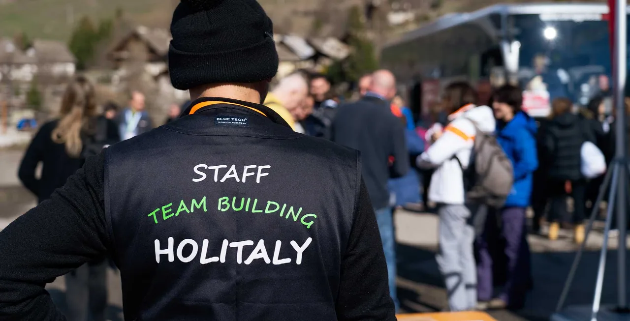 Membro dello staff Holitaly durante un evento di team building, con i partecipanti sullo sfondo